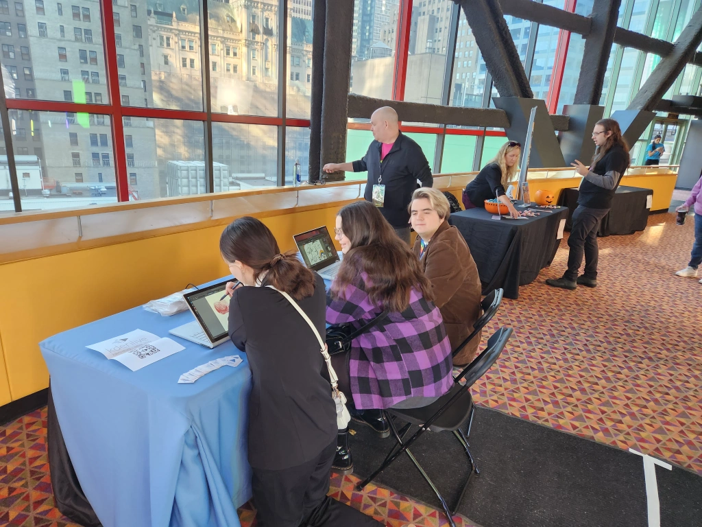 Attendees sit drawing on a tablet at the KDE booth.