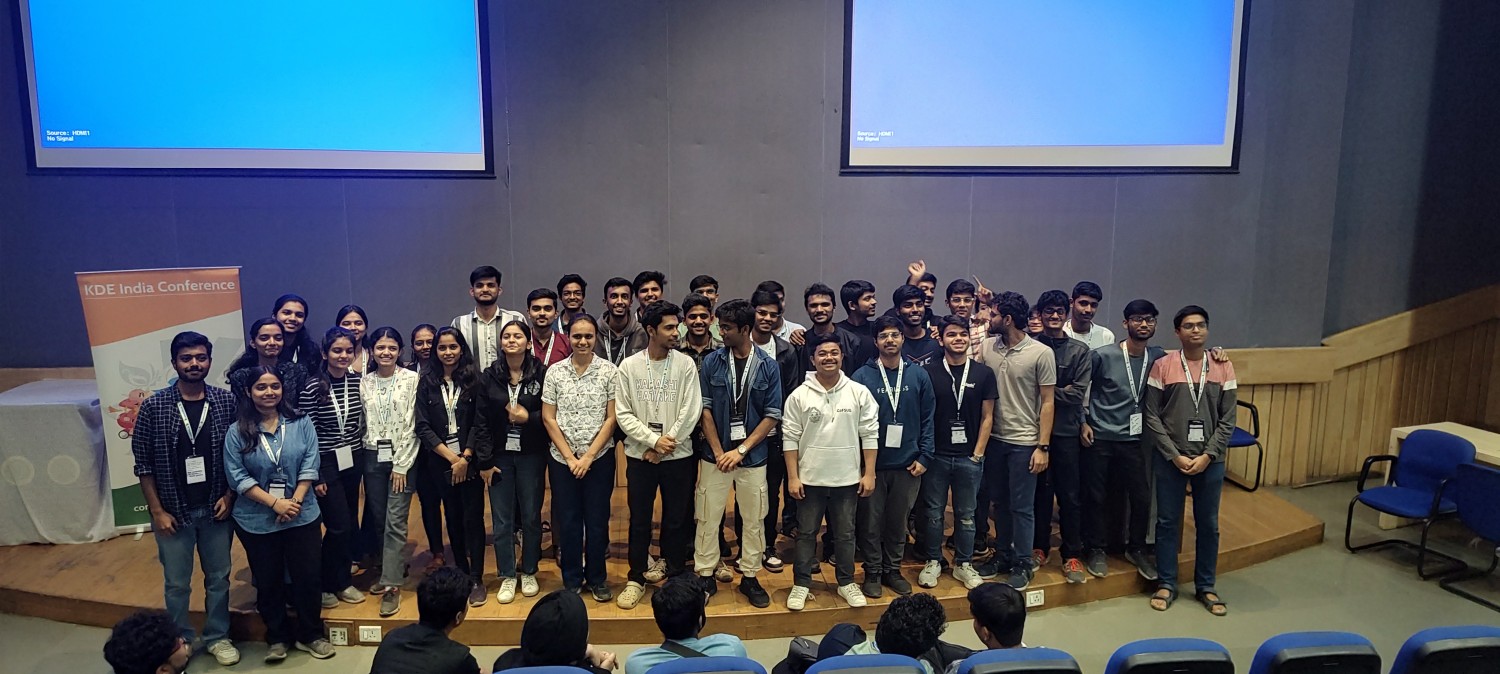 Attendees to con.kde.in pose in a conference hall.